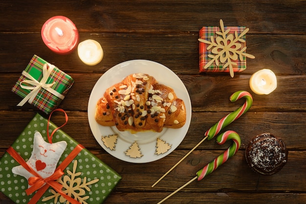 Mesa de la mañana de Navidad con croissant (panadería), dulces y regalos. Vista superior de regalos navideños, decoración.