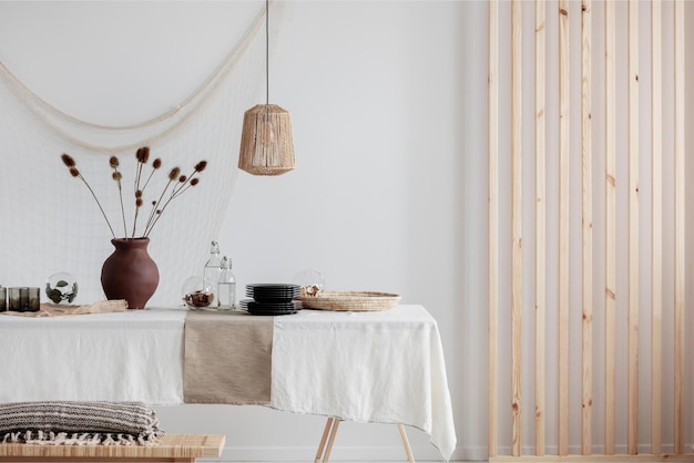 Una mesa con un mantel blanco y una mesa de madera con un jarrón de flores.