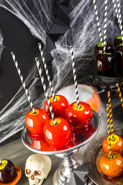 Foto mesa con manzanas de caramelo de colores para la fiesta de halloween.