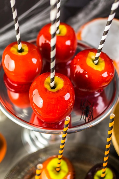 Mesa con manzanas de caramelo de colores y pastel para fiesta de Halloween.