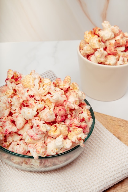 Mesa de mármol con cuencos de vidrio y cerámica con palomitas de maíz rosa