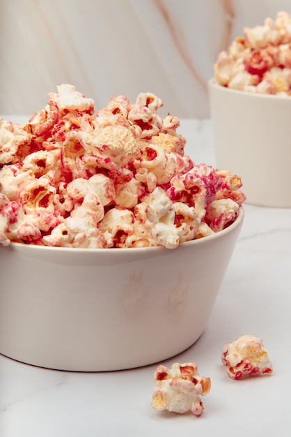 Mesa de mármol con cuencos de vidrio y cerámica con palomitas de maíz rosa