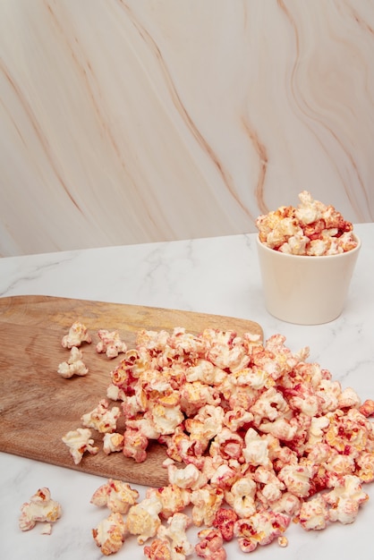 Mesa de mármol con cuencos de vidrio y cerámica con palomitas de maíz rosa