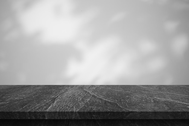 Mesa de mármol con sombra de árbol sobre fondo de pared blanca para exhibición de productos de maqueta