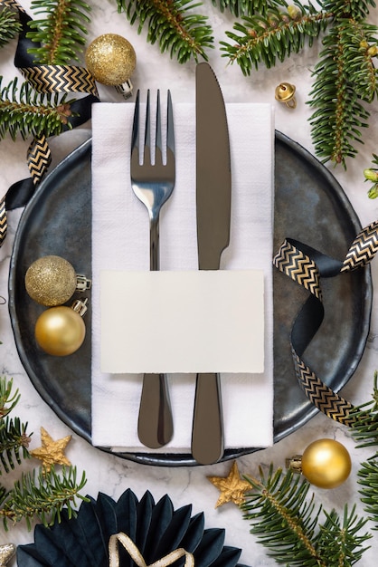 Mesa de Navidad negra y dorada con adornos de tarjetas de lugar y ramas de abeto Mockup