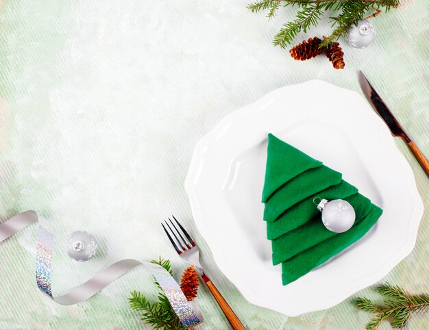 Mesa de Navidad con platos blancos y verde servilleta de árbol de Navidad doblar en verde claro. Vista superior, copyspace