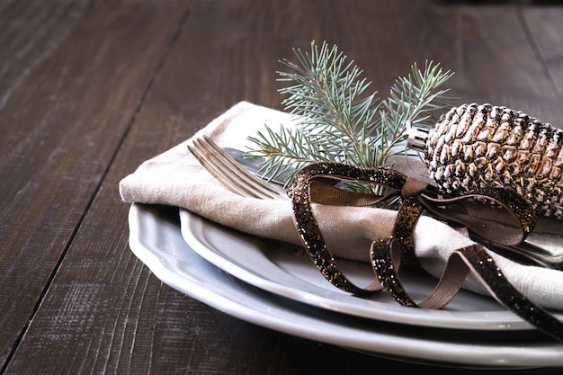 Mesa navideña con platería y decoración perenne natural oscura.