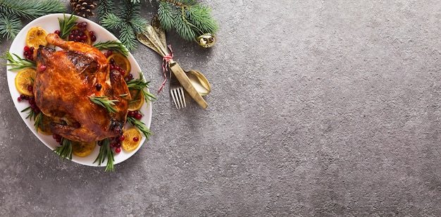 La mesa navideña con pollo al horno está decorada festivamente con velas.