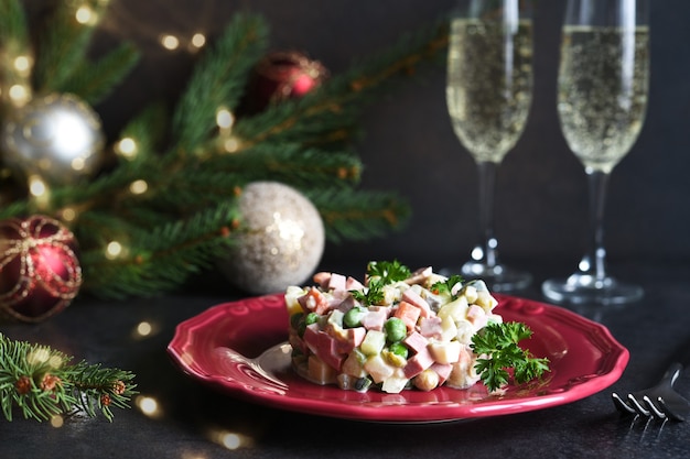 Mesa navideña tradicional con ensalada Olivier, copas de champán y decoración