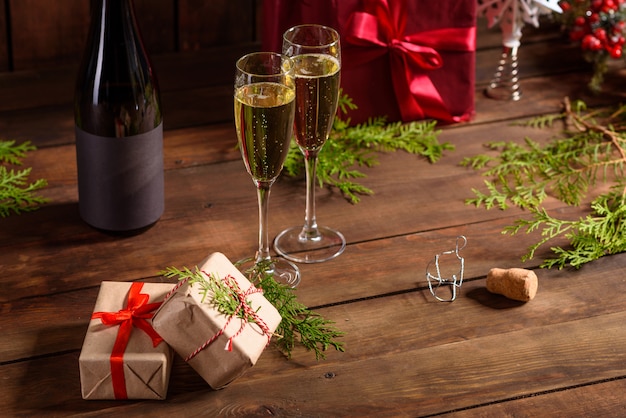 Mesa navideña con vasos y una botella y regalos