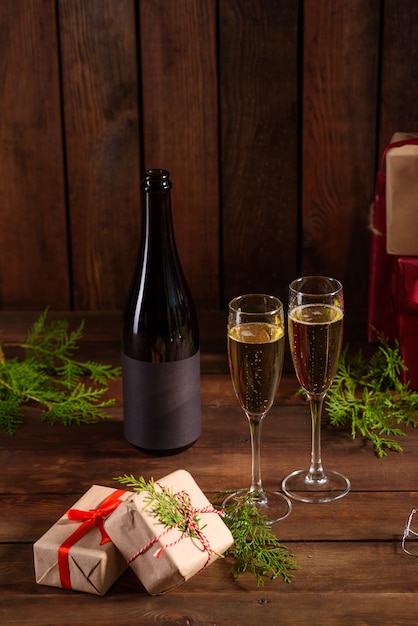 Mesa navideña con vasos y una botella y regalos