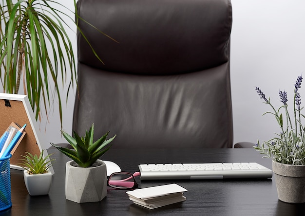 Mesa negra con papelería, teclado inalámbrico, mouse, lugar de trabajo de un líder