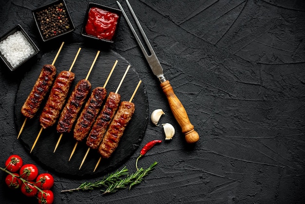 Foto una mesa negra con una parrilla con kebabs encima.