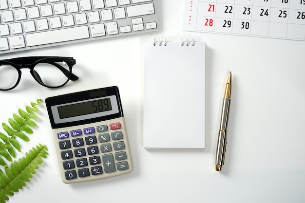 Mesa de oficina con herramientas informáticas de cuaderno en blanco Calculadora Calendario de cuaderno y suministros de oficina Arriba
