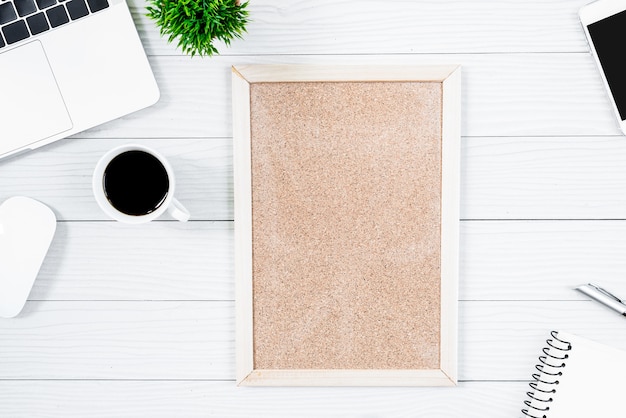 Mesa de oficina de madera blanca y equipo para trabajar con café negro y tablero en blanco