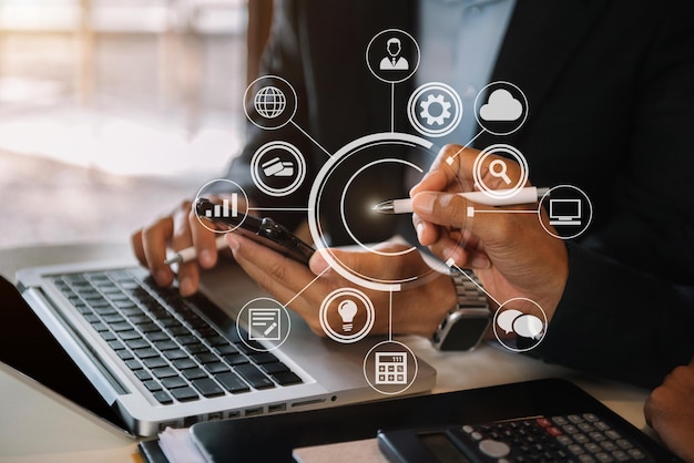 Mesa de oficina de negocios con tableta de teléfono inteligente y computadora portátil y gráfico con diagrama de red social y dos colegas discutiendo datos en la oficina