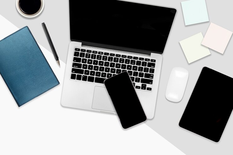 Foto mesa de oficina plana con ordenador portátil, tableta digital, teléfono móvil y accesorios.