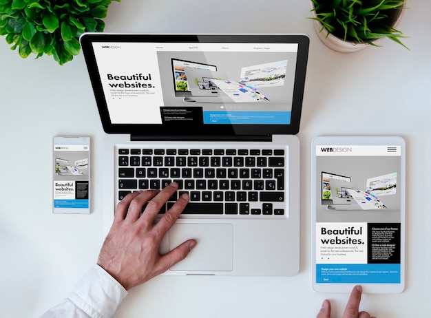 Mesa de oficina con tableta, teléfono inteligente y computadora portátil que muestra un sitio web de diseño receptivo y genial