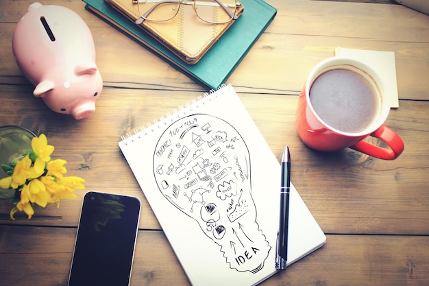 Foto mesa de oficina con una taza de café, un plan en el bloc de notas