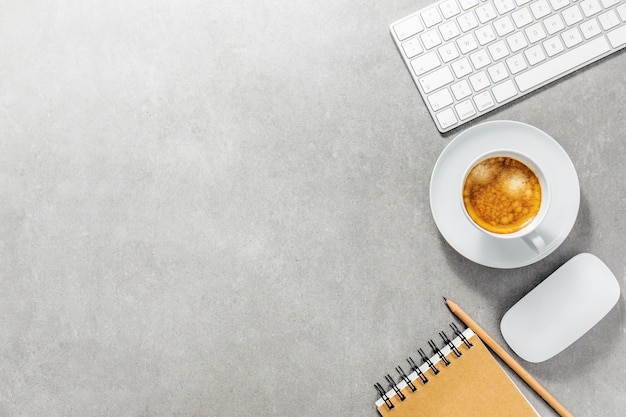 Mesa de oficina con taza de café, teclado y bloc de notas.