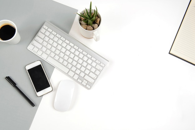 Foto mesa de oficina con teclado, mouse y teléfono inteligente en el moderno bacalao de dos tonos (blanco y gris)