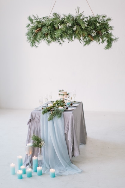 Mesa para convidados, decorada com velas, servida com talheres e louça e coberta com uma toalha de mesa