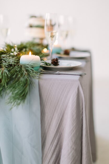 Mesa para convidados, decorada com velas, servida com talheres e louça e coberta com uma toalha de mesa