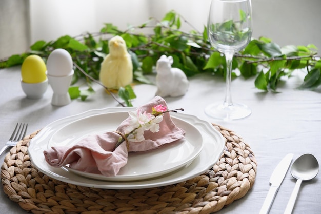 Mesa de pascua con decoración de pollitos amarillos, flores frescas y huevos, cena elegante en casa.