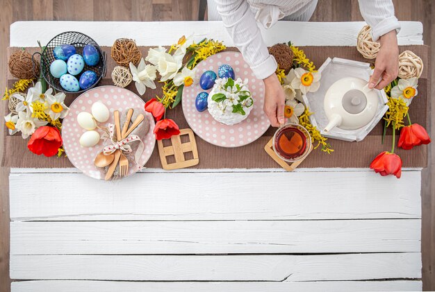 Mesa de Pascua festiva con tarta de Pascua casera, té, flores y detalles decorativos copie el espacio. Concepto de celebración familiar.