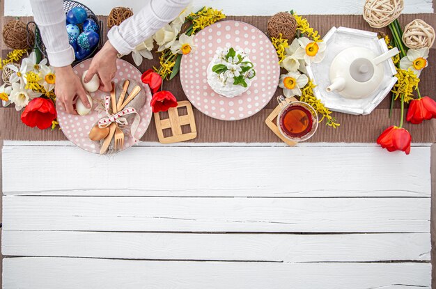 Mesa de Pascua festiva con tarta de Pascua casera, té, flores y detalles decorativos copie el espacio. Concepto de celebración familiar.