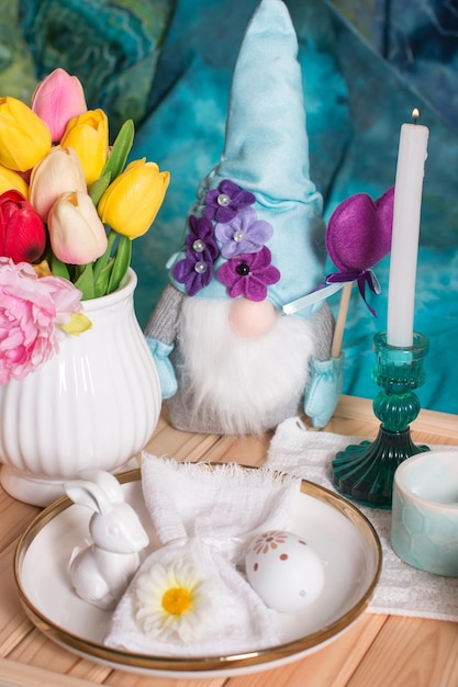 Mesa de Pascua romántica con velas un plato de punto blanco una taza con una bebida Decoración de mesa con conejo y huevos pintados