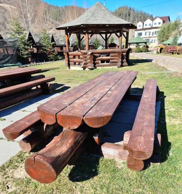 Una mesa de picnic de madera está en la hierba con un cenador en el fondo