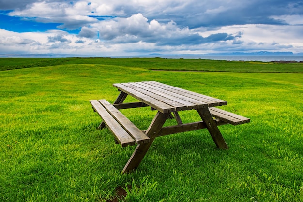 Mesa de picnic de madera en Islandia, en el prado verde. Fondo de verano al aire libre de viaje