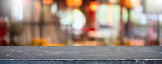 Mesa de piedra de mármol negro vacía y centro comercial interior de ventana de vidrio borroso