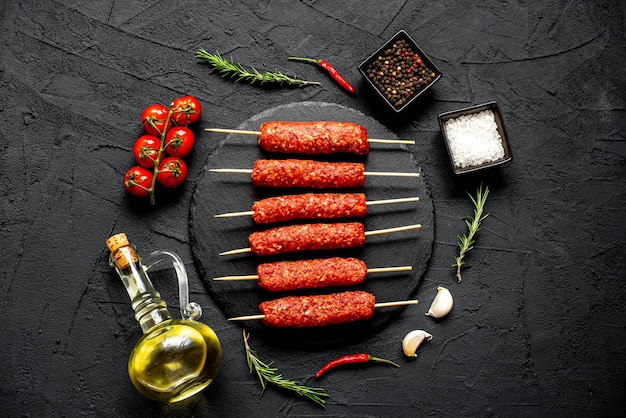 Una mesa de piedra negra con una variedad de brochetas de carne y aceite de oliva.