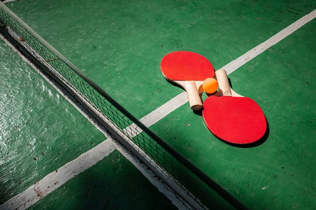 Mesa de ping pong, raqueta y juego de pelota en la naturaleza.