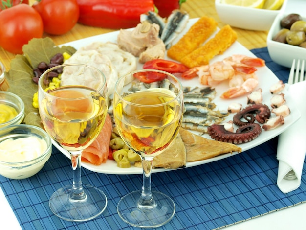 Una mesa con un plato de comida y copas de vino y una botella de vino.