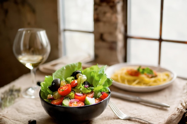 Una mesa con un plato de ensalada y una copa de vino.