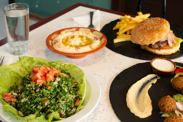 Mesa con platos árabes y una hamburguesa falafel hummus de garbanzos con aceite y pimentón Ensalada turca