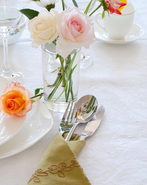 Mesa con platos cubiertos y flores.