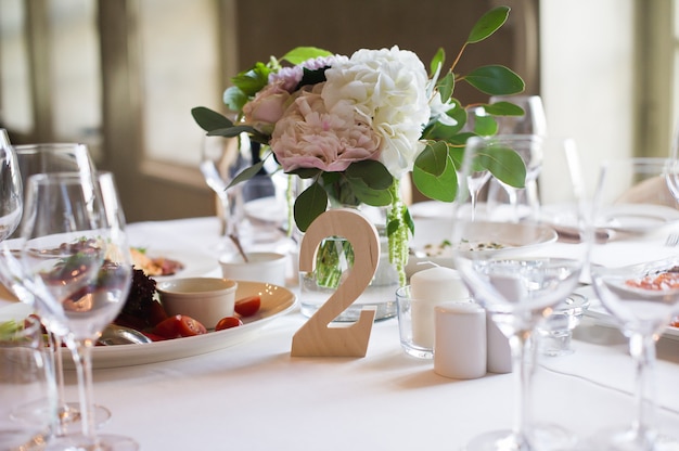 Mesa posta no banquete de casamento no restaurante, estilo clássico com toalhas de mesa e guardanapos brancos, vasos com flores.