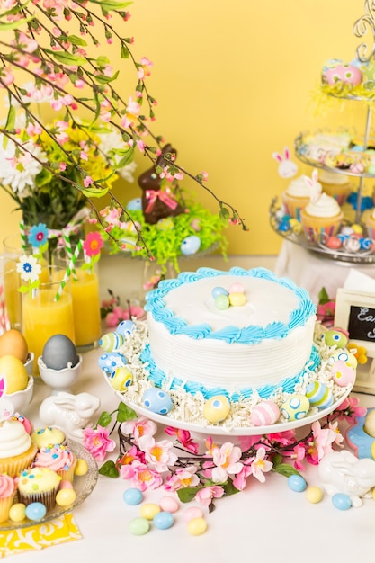 Mesa de postres con pastel y cupcakes para el brunch de Pascua.