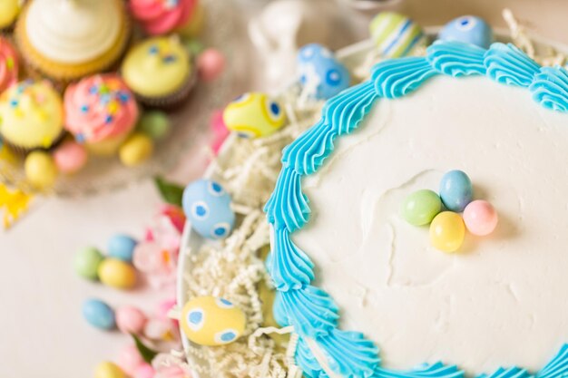 Mesa de postres con pastel y cupcakes para el brunch de Pascua.