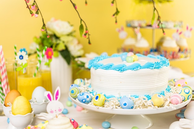 Mesa de postres con pastel y cupcakes para el brunch de Pascua.