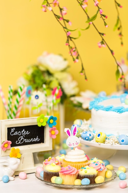 Mesa de postres con pastel y cupcakes para el brunch de Pascua.