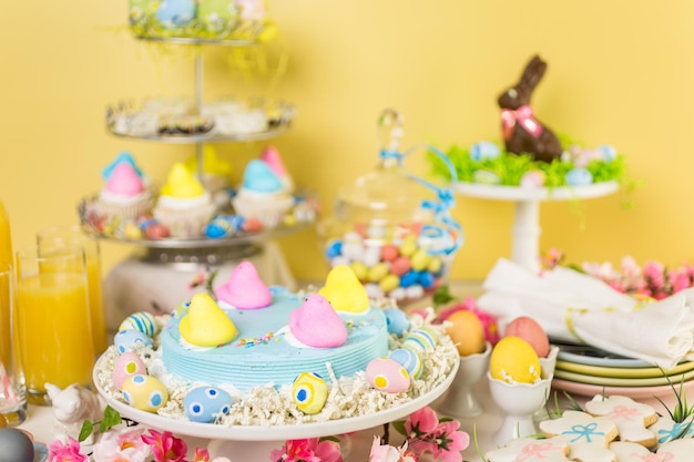 Mesa de postres con pastel de Pascua decorado con polluelos de malvavisco tradicionales de Pascua.