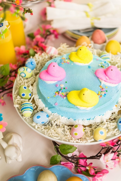 Mesa de postres con pastel de Pascua decorado con polluelos de malvavisco tradicionales de Pascua.