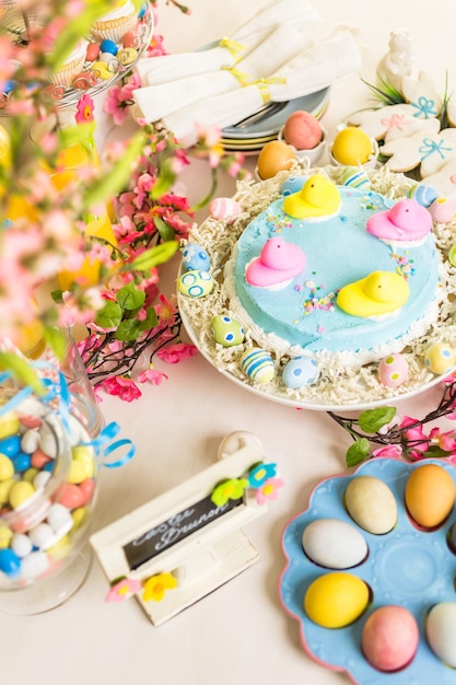 Mesa de postres con pastel de Pascua decorado con polluelos de malvavisco tradicionales de Pascua.