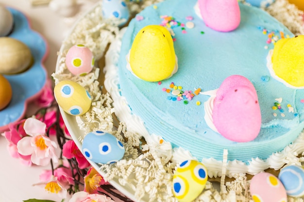 Mesa de postres con pastel de Pascua decorado con polluelos de malvavisco tradicionales de Pascua.