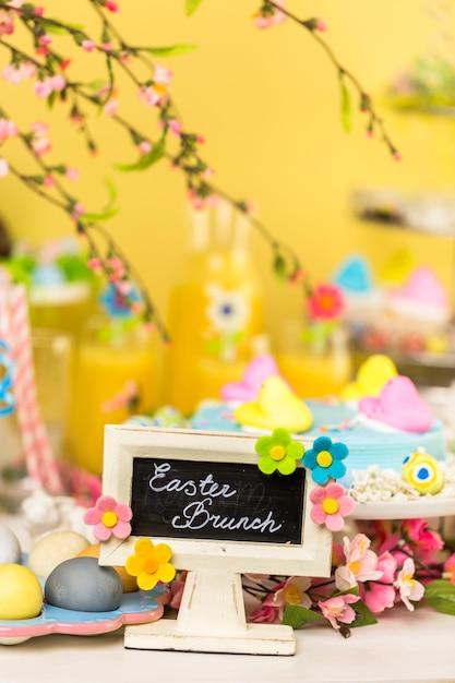 Foto mesa de postres con pastel de pascua decorado con polluelos de malvavisco tradicionales de pascua.